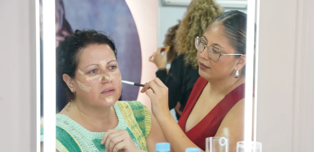 Mentora de C•A Academy aplicando técnicas de corrección facial a una alumna durante una clase práctica de maquillaje profesional.