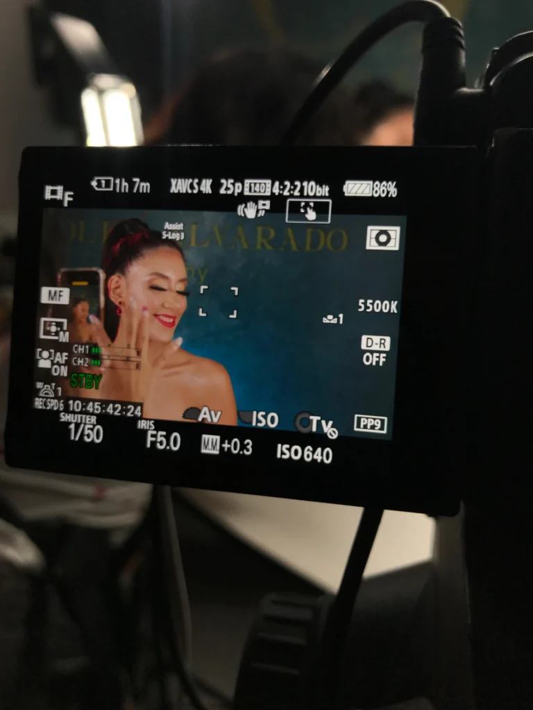 Primer plano de una cámara grabando a una modelo maquillada en un tutorial profesional