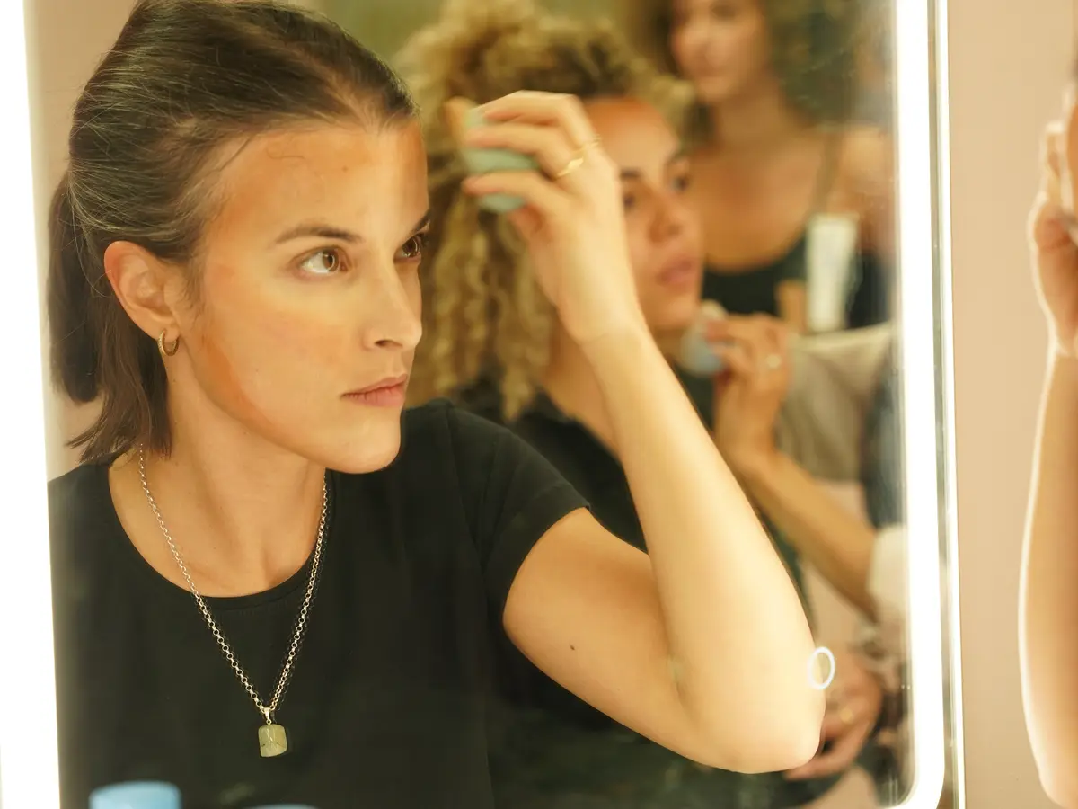 Formación práctica para maquilladoras profesionales Alumna practicando maquillaje frente al espejo durante una formación profesional