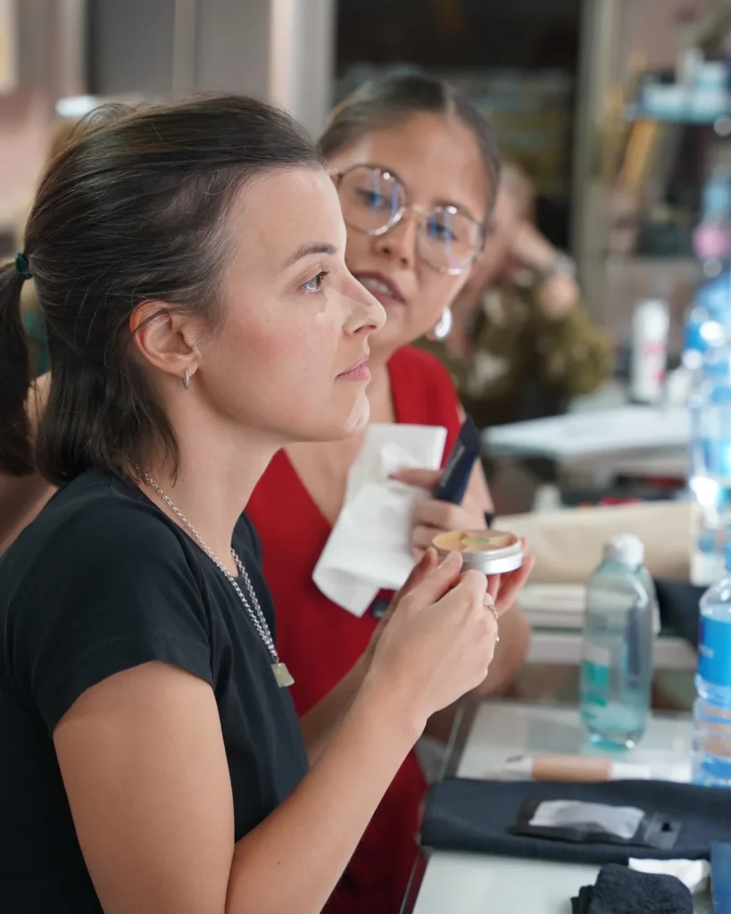 Alumna con productos de maquillaje durante una práctica guiada frente al espejo