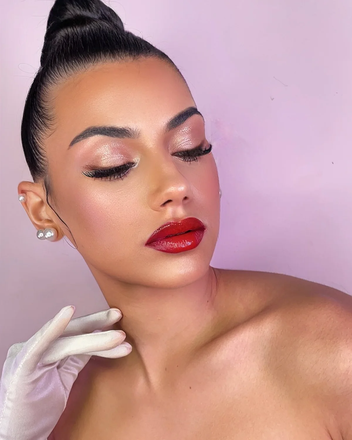 Primer plano de maquillaje luminoso con sombras rosadas, delineado y labios rojos