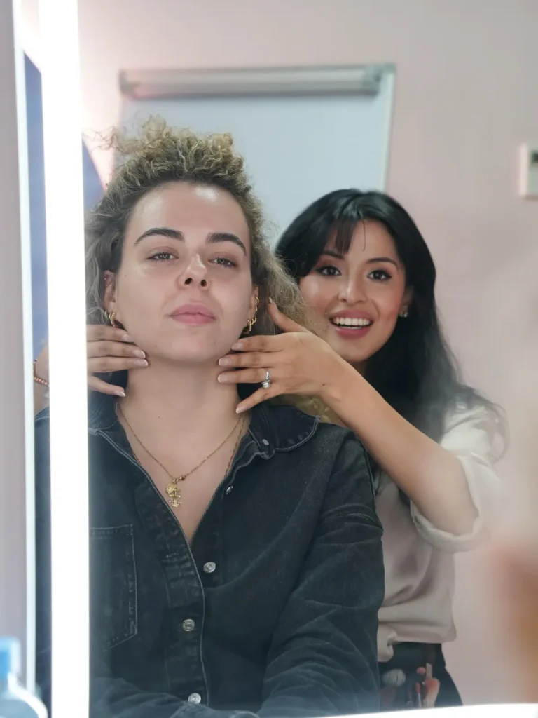Maquilladora profesional trabajando con una clienta frente al espejo