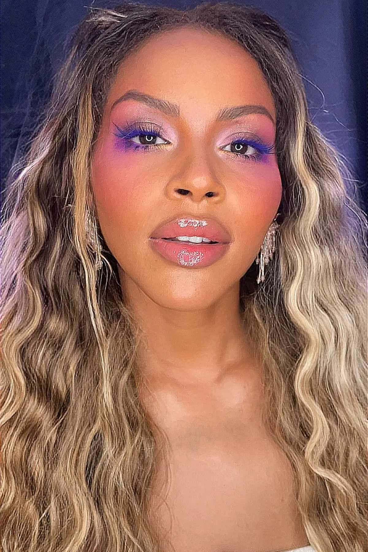Maquillaje personalizado para conseguir clientas recurrentes Primer plano de una mujer con maquillaje profesional de ojos en tonos rosa y violeta